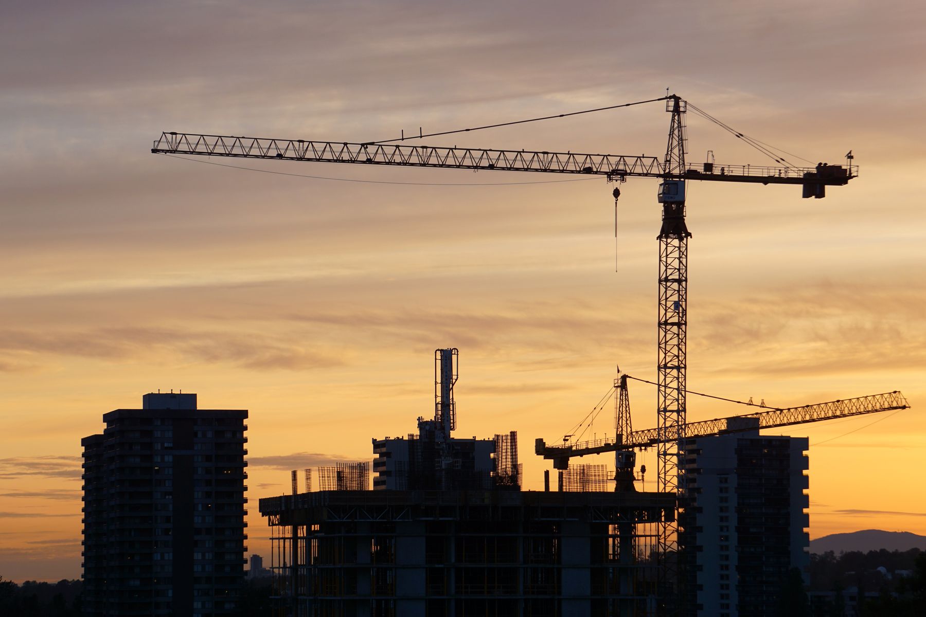 Tower cranes over a new development at sunset
